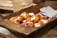 Freshly baked pastries with icing in a rustic wooden tray, perfect for cozy kitchen scenes.
