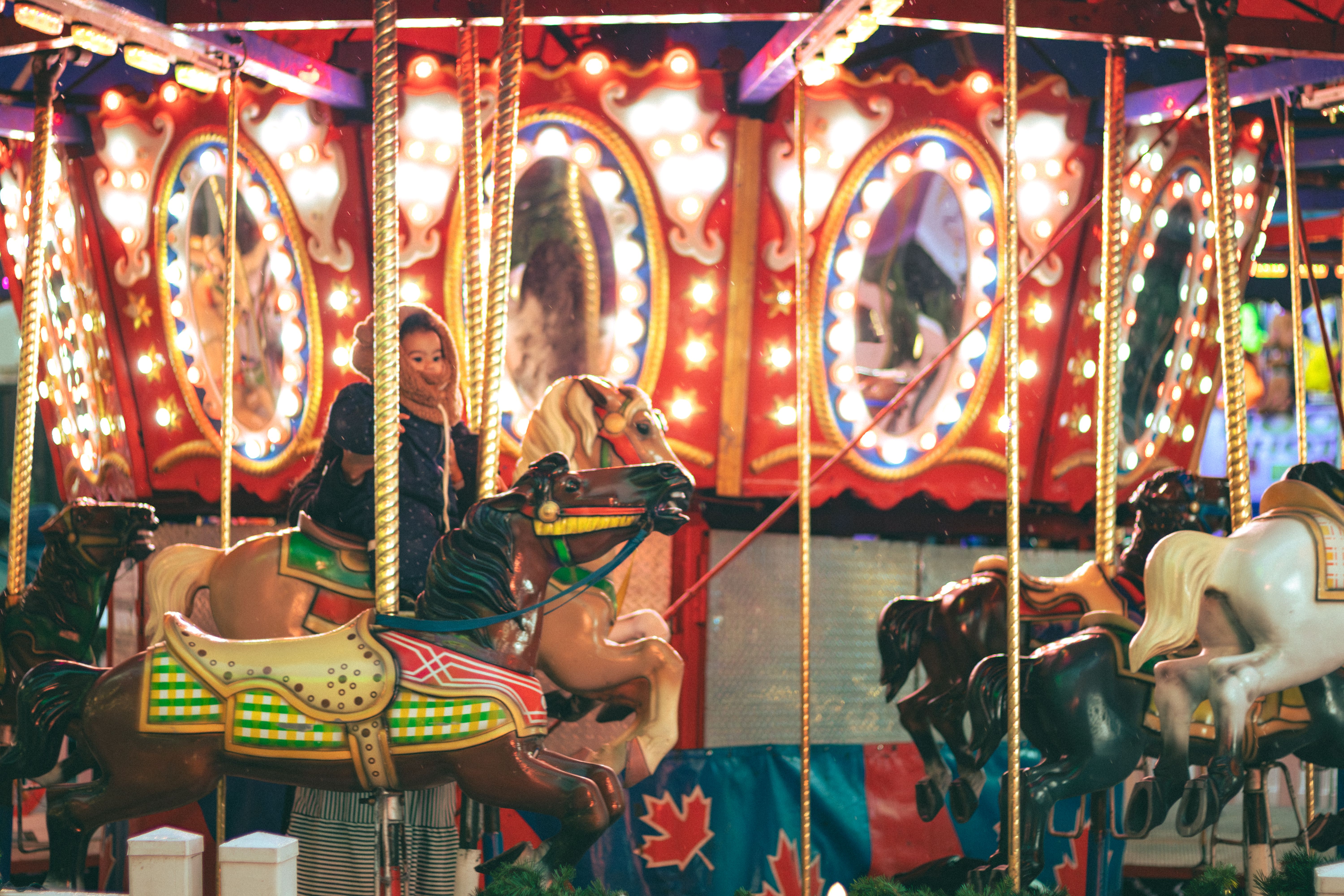 Joyful carousel ride with children at night in Toronto's amusement park, full of vibrant colors and lights.