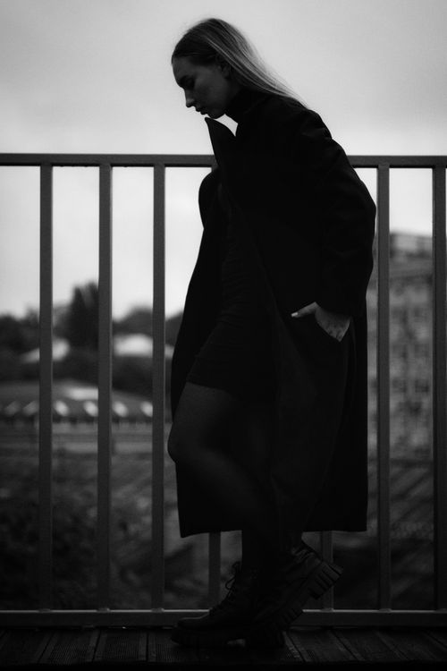 Free Black and white silhouette of a woman walking on a bridge in an urban setting. Stock Photo