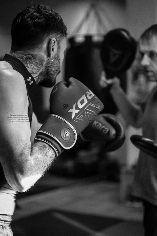 Free Black and white photo of a boxer training intensely with a coach in a gym. Stock Photo