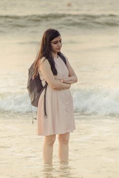 Thoughtful woman stands at the edge of Vagator Beach, Goa at sunset, embodying tranquility.
