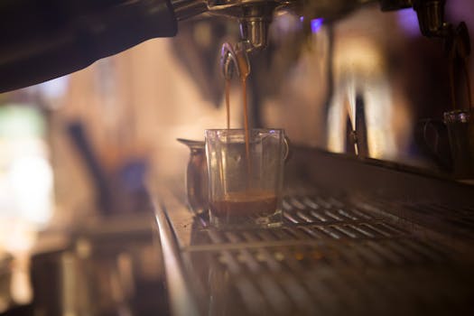 Close-up of espresso being brewed into a glass cup at a coffee shop.