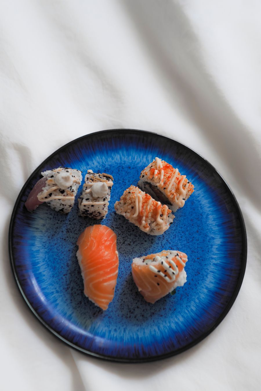 Assortiment de nigiris et de makis sur une assiette bleue, photographie d’illustration