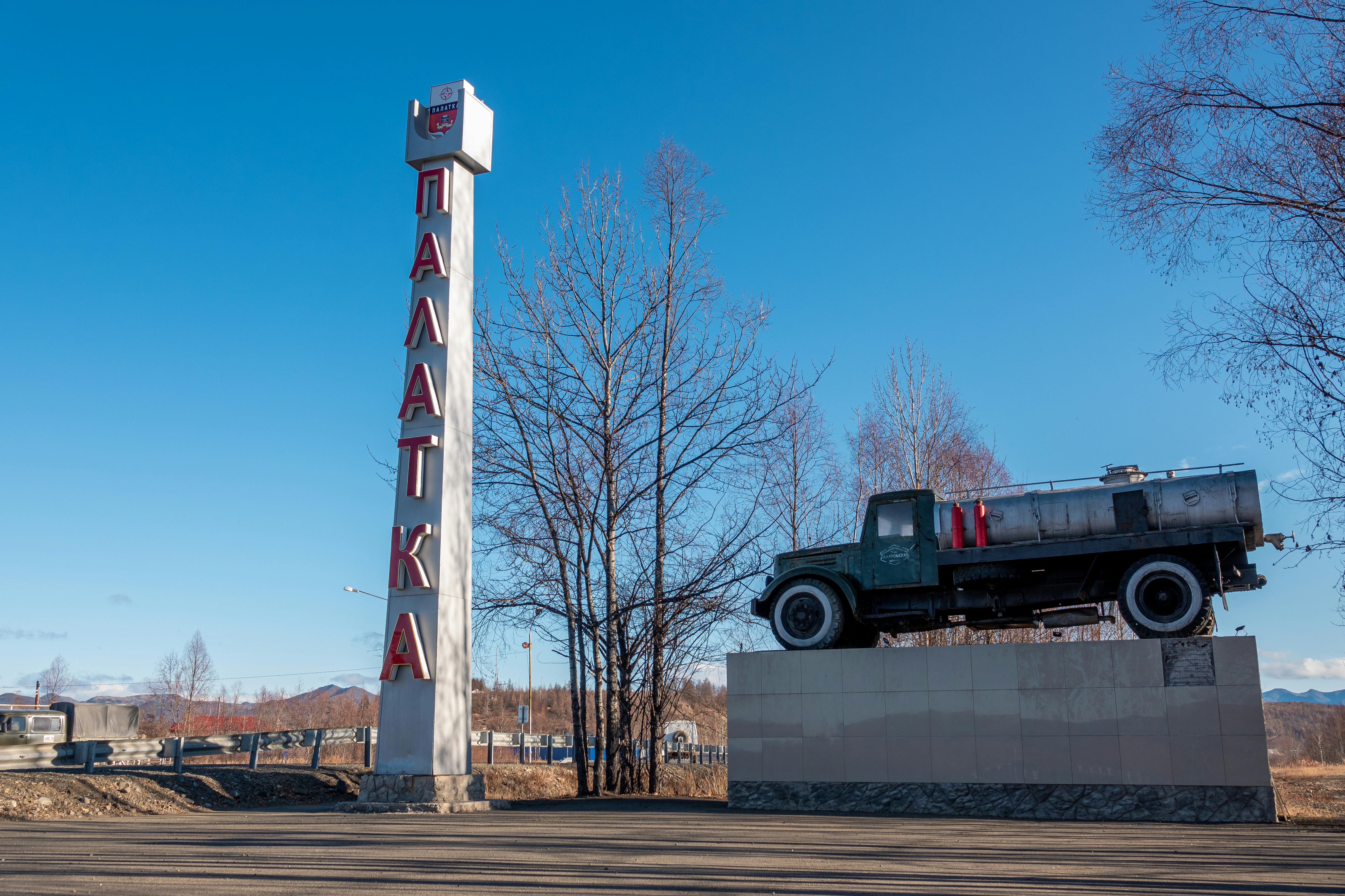 Monument with vintage truck and tall Palatka sign with blue sky backdrop.