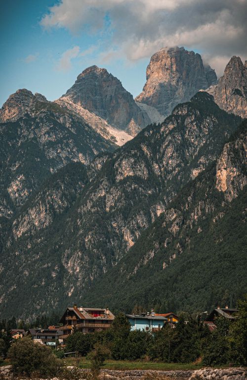 Free Charming village nestled at the foothills of towering mountain peaks in scenic alpine region. Stock Photo