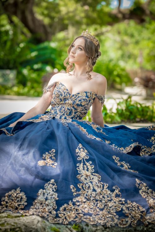 Free A woman in a stunning royal blue gown with golden embroidery, sitting outdoors. Stock Photo