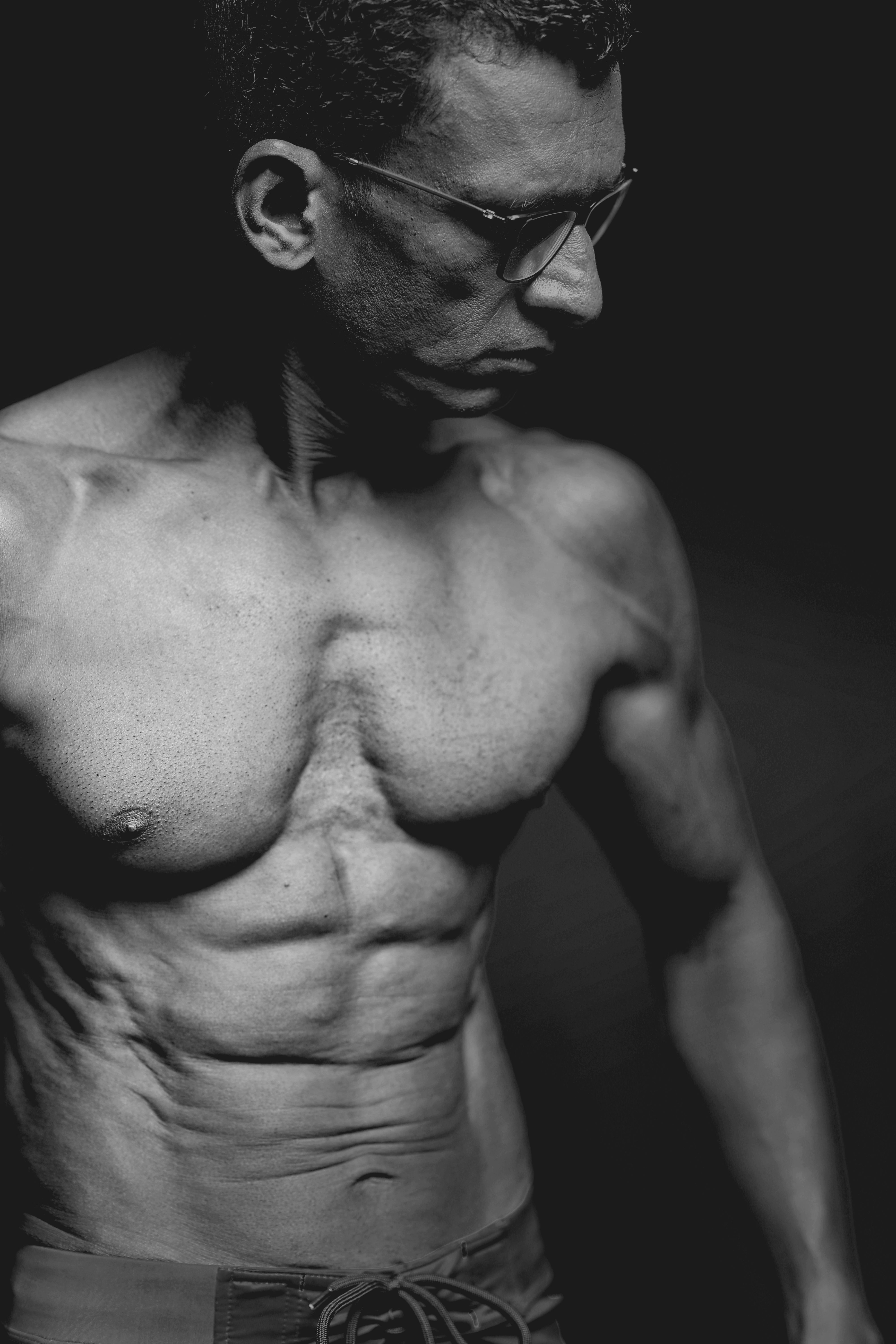 Dramatic monochrome photo of a muscular adult male posing in a studio.