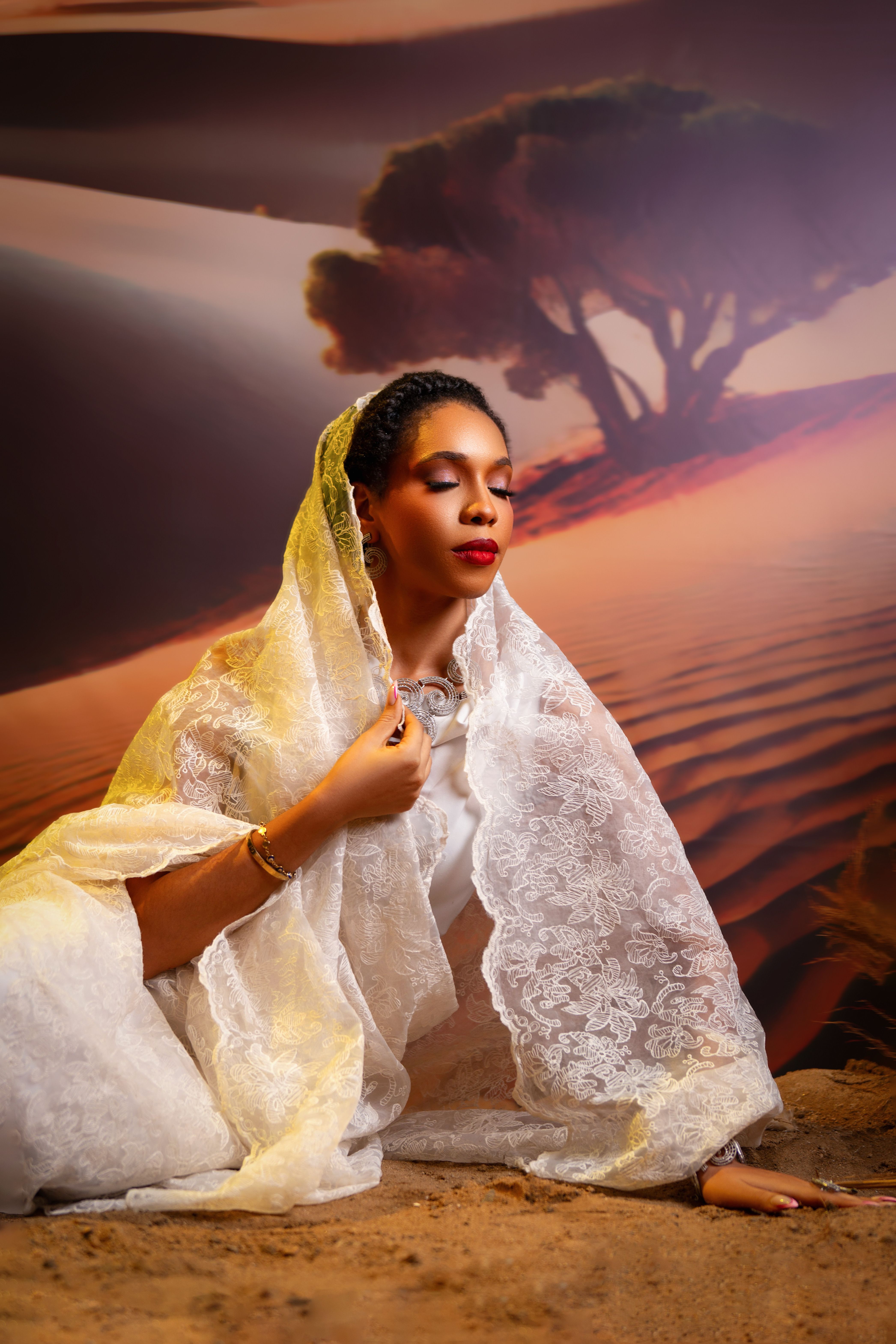 A Nigerian woman wears traditional white attire in a serene desert setting.