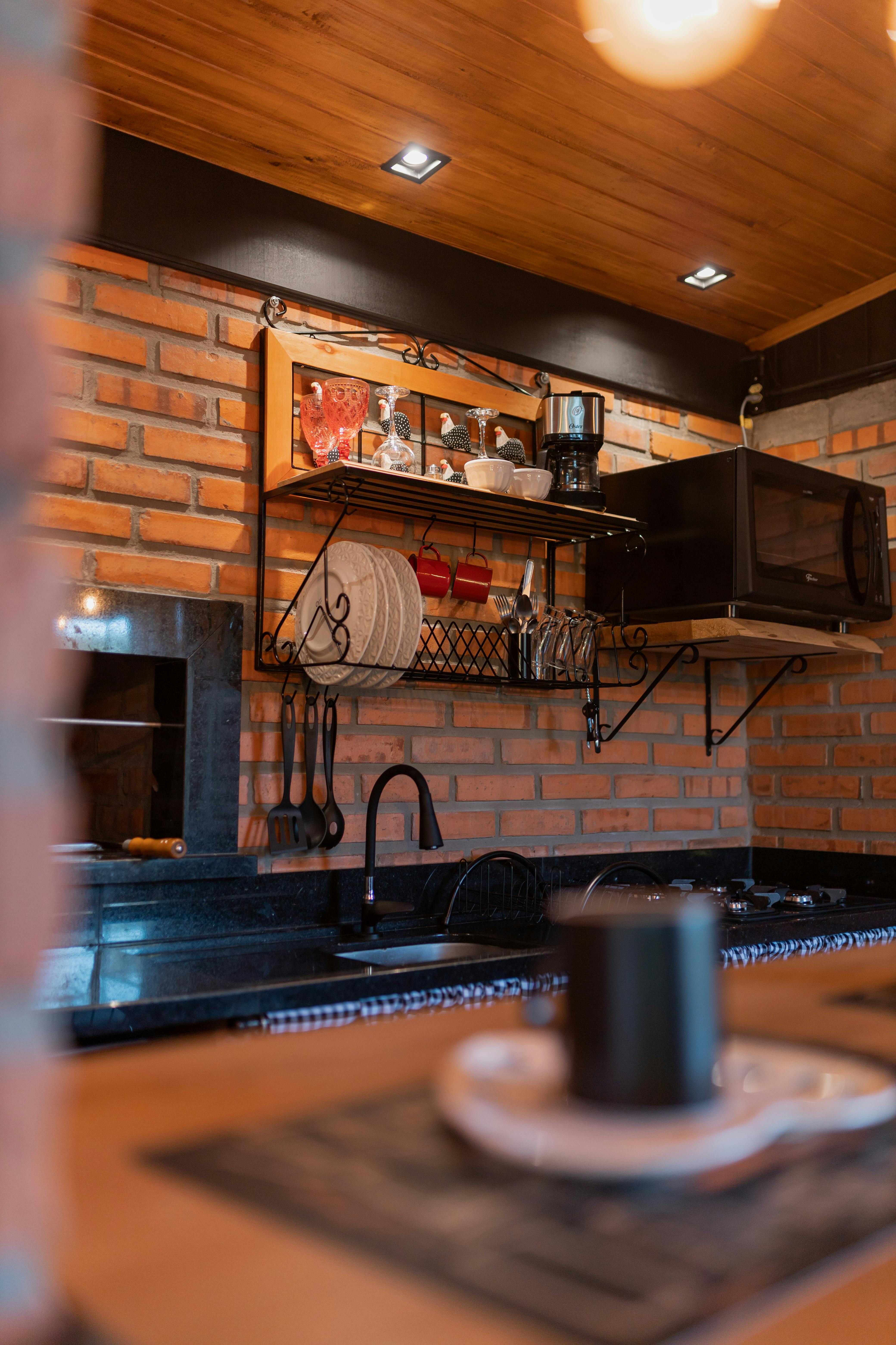 Warm and inviting kitchen featuring rustic brick walls, wooden shelves, and modern appliances.