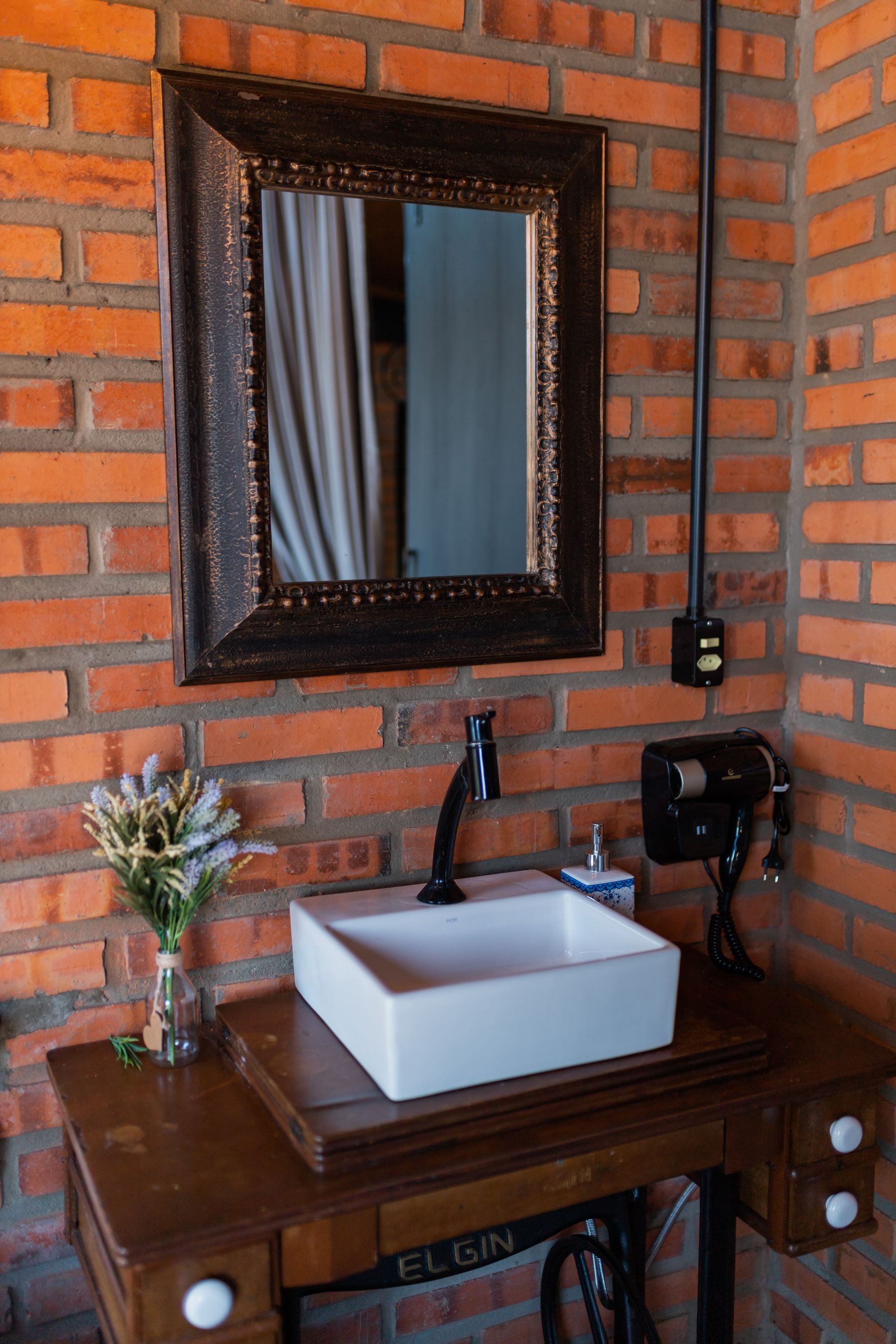 Bathroom vanity against an exposed brick wall with simple contemporary fittings