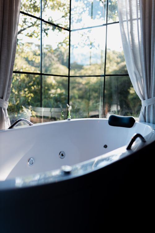 Free Elegant bathtub by large window with a breathtaking nature view, perfect for relaxation. Stock Photo