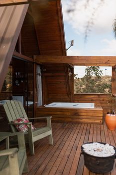 A tranquil rustic cabin featuring an outdoor deck, seating, and a hot tub, perfect for relaxation.