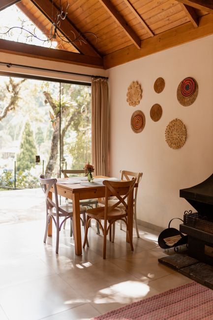 Fotomural Comedor rústico con vista soleada, con mesa de madera y detalles decorativos en la pared.