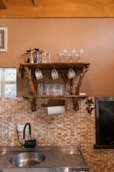 Cozy rustic kitchen setup featuring wooden shelves with glassware and mugs.