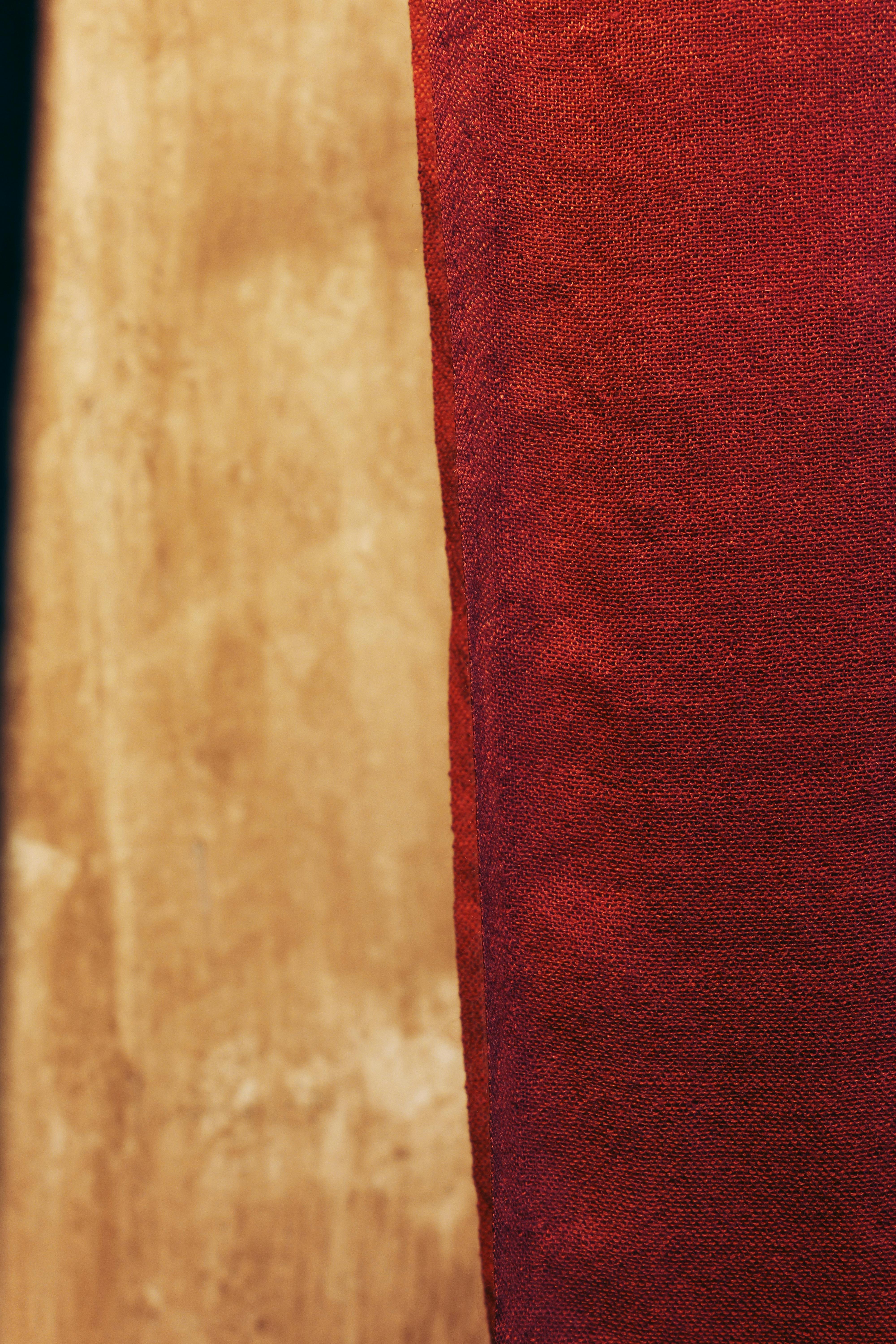 Free A detailed close-up of red textured fabric against a smooth wooden background. Stock Photo