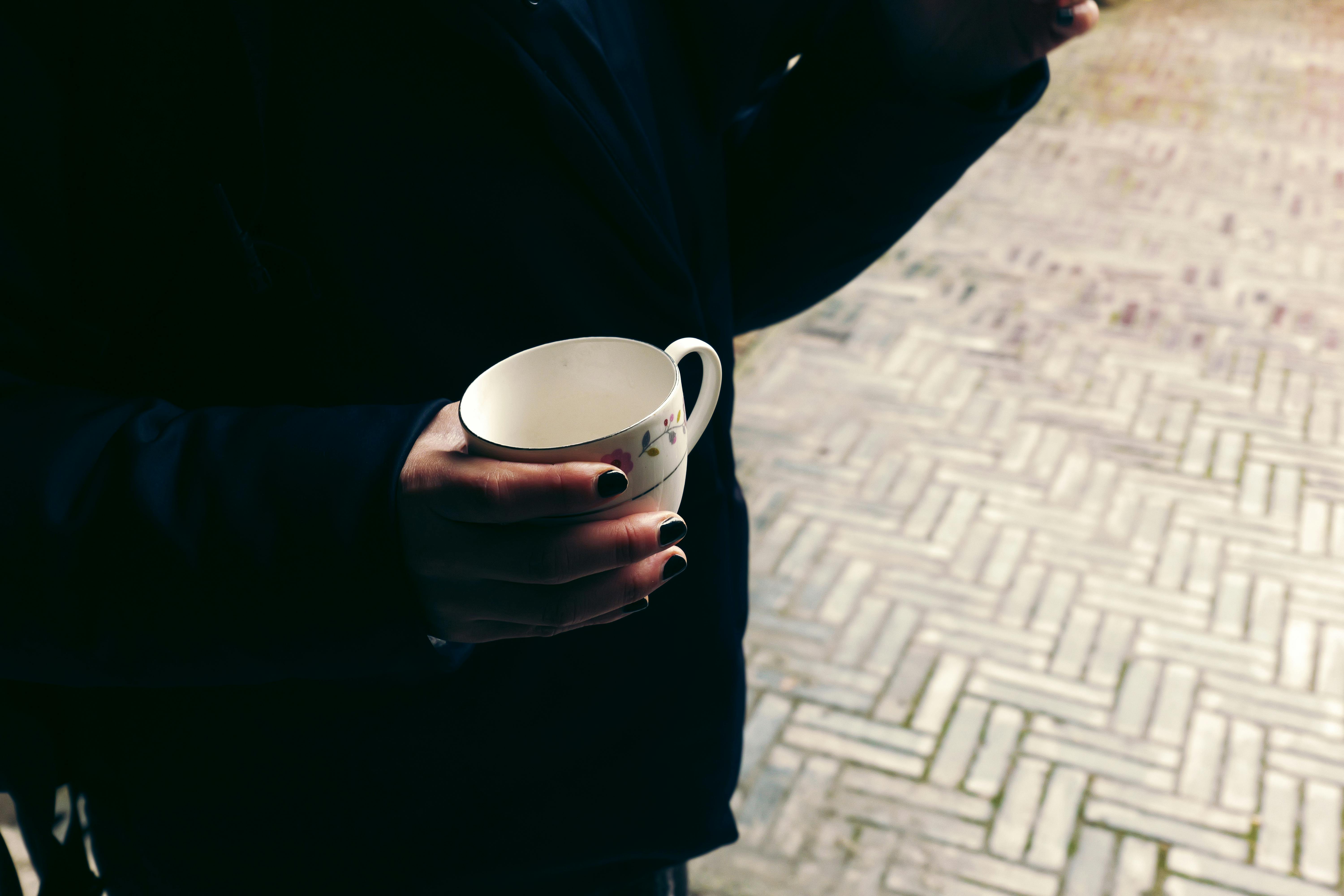 Zadarmo Detailný záber na dospelého, ktorý vonku drží biely pohár na textúrovanom tehlovom povrchu. Fotka z fotobanky