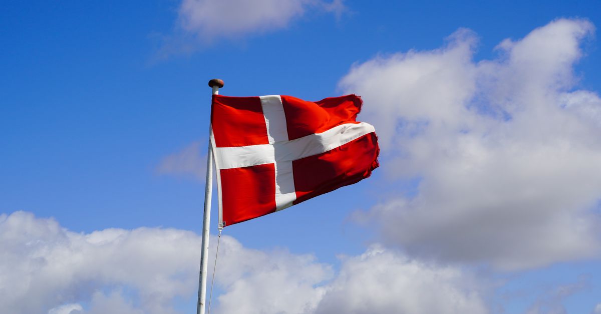 Rüyada Yabancı Bir Ülkede Olmak - Rüya Tabiri ve Anlamı - Danish flag waving proudly against a blue sky with fluffy clouds, symbolizing national pride.