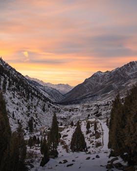 Breathtaking view of a vibrant winter sunset casting golden light over a serene snow-covered valley.