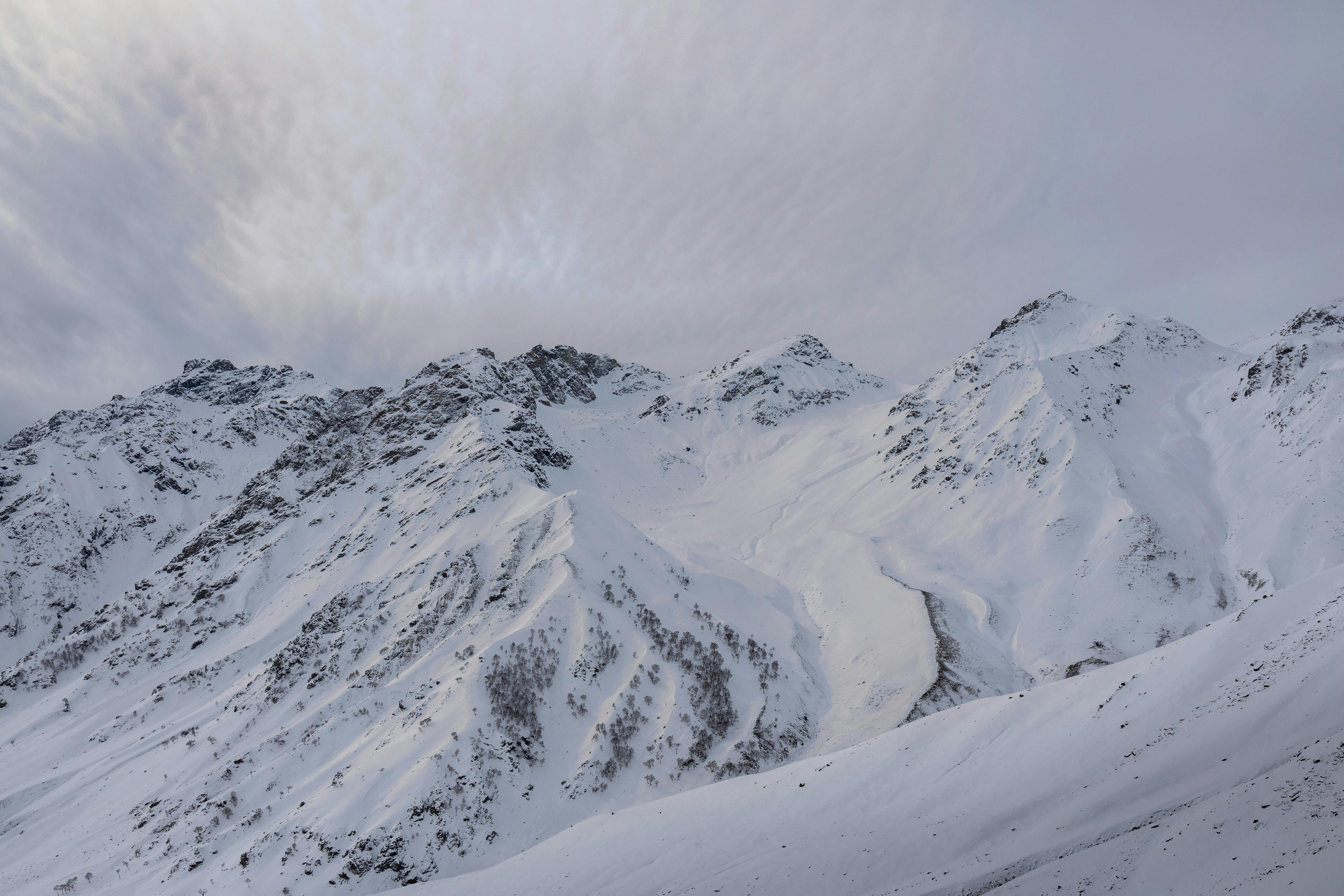 Explore the serene beauty of snow-covered mountain peaks under soft winter light.