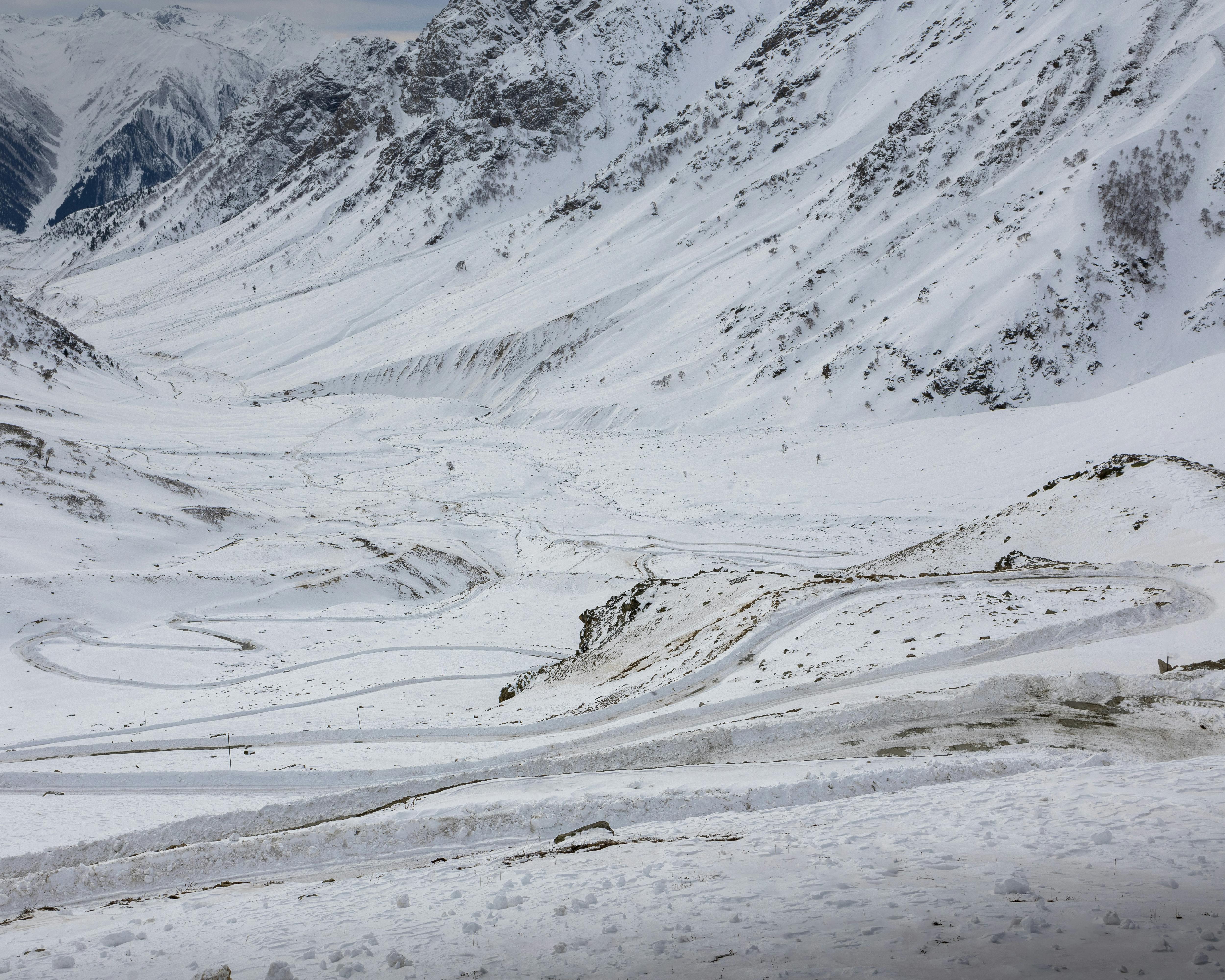 A breathtaking landscape of snow-covered mountains with winding roads under a winter sky.