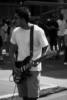 A stylish street musician passionately plays an electric guitar during a lively outdoor performance.