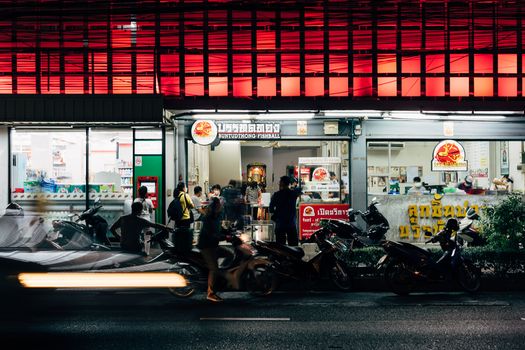Bustling night market scene with people and street food in Thailand, featuring a fishball shop.
