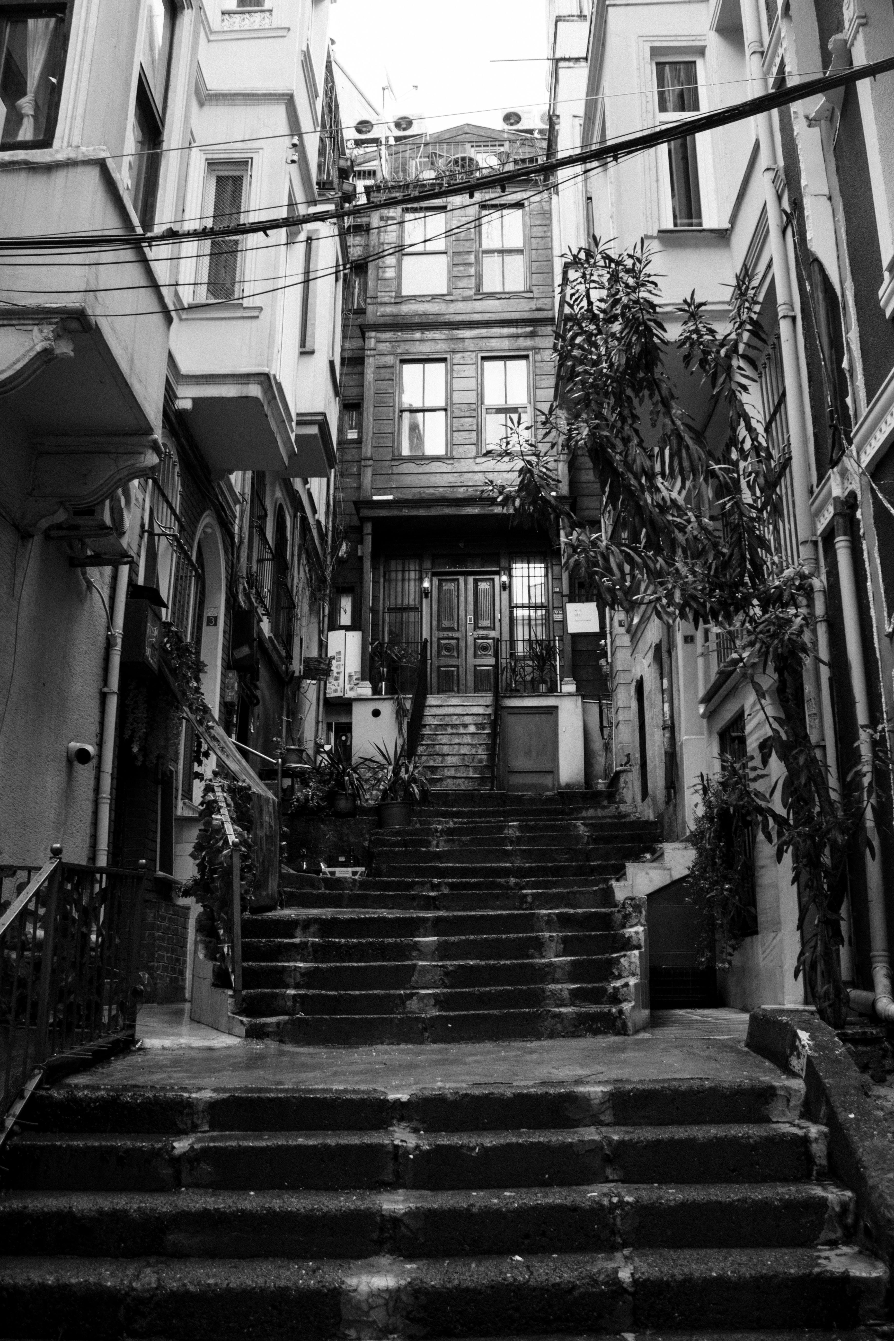 Black and white image of a narrow historic alleyway featuring stone steps and classic architecture.
