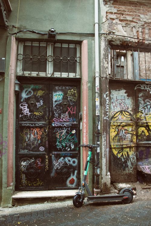 Free Graffiti-covered door and wall with an abandoned scooter on a gritty urban street. Stock Photo