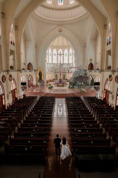 Bride and groom walk down the aisle in a stunning, large church with high arches and elegant décor.