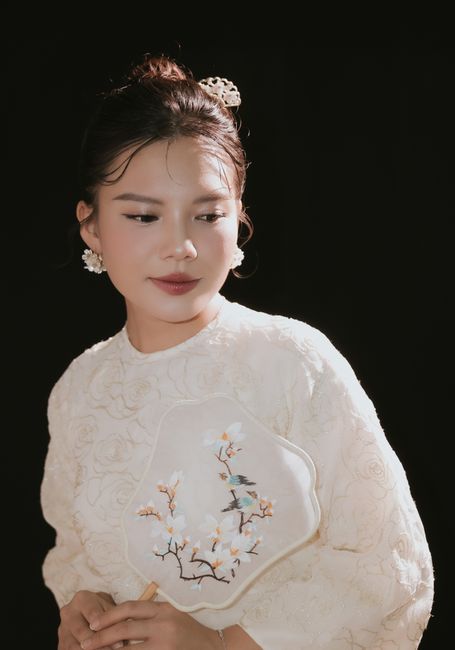A woman gracefully holds a traditional fan, showcasing elegance and culture.