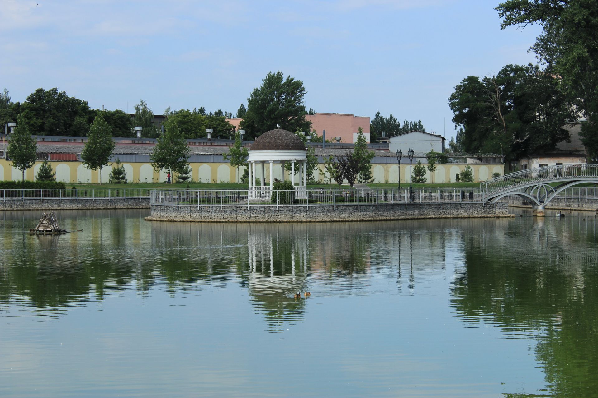 Elegant gazebo surrounded by a peaceful park lake view, perfect for relaxation.