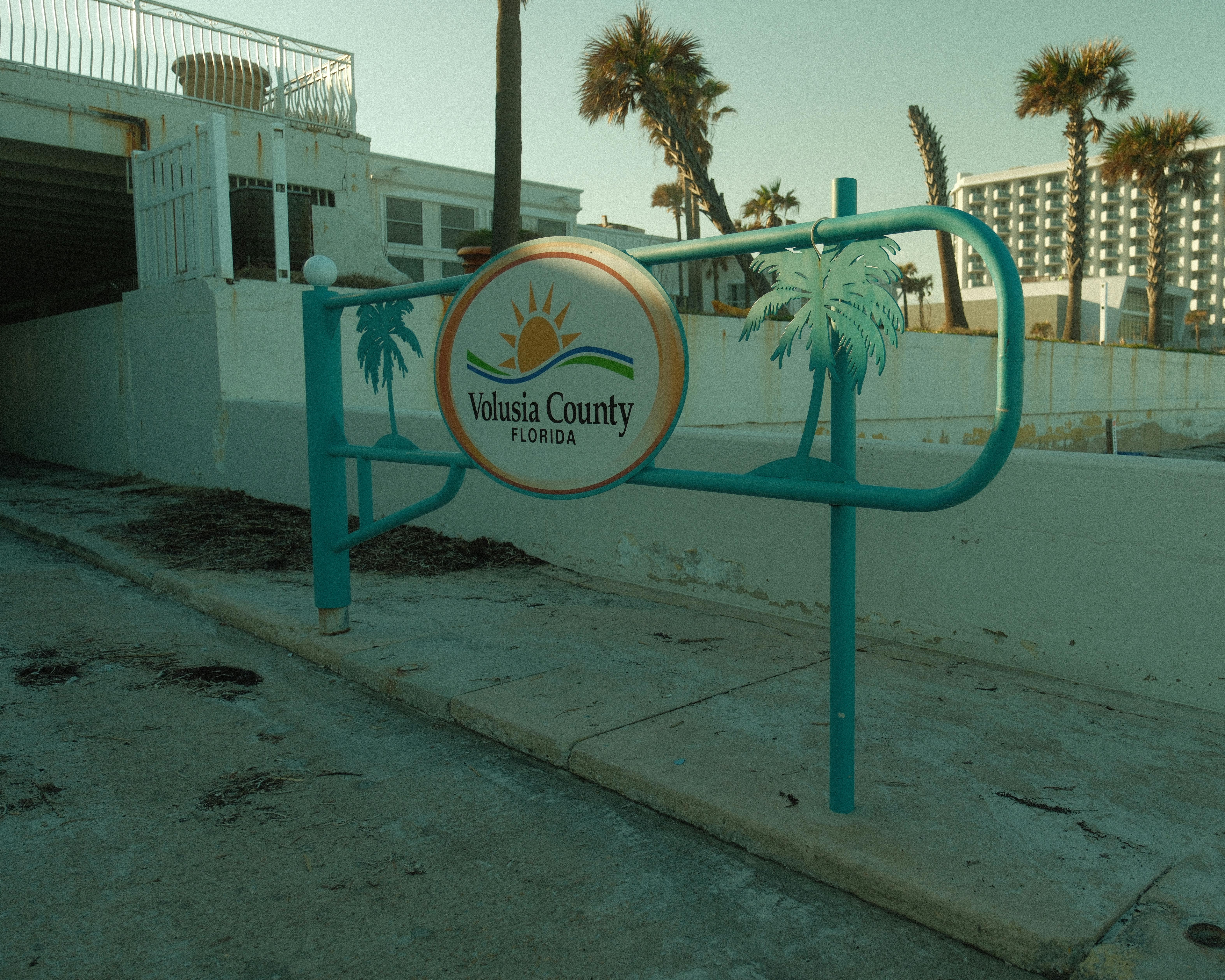 Sign at Volusia County, Florida beachfront entrance with palm trees.