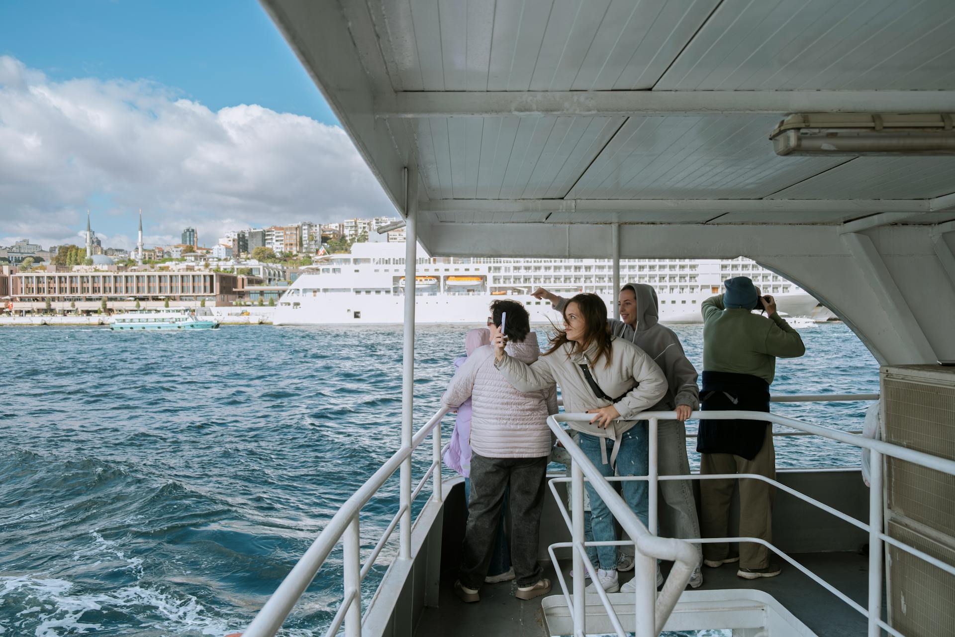 Tourists enjoy a boat ride on the Bosphorus in Istanbul with city views.