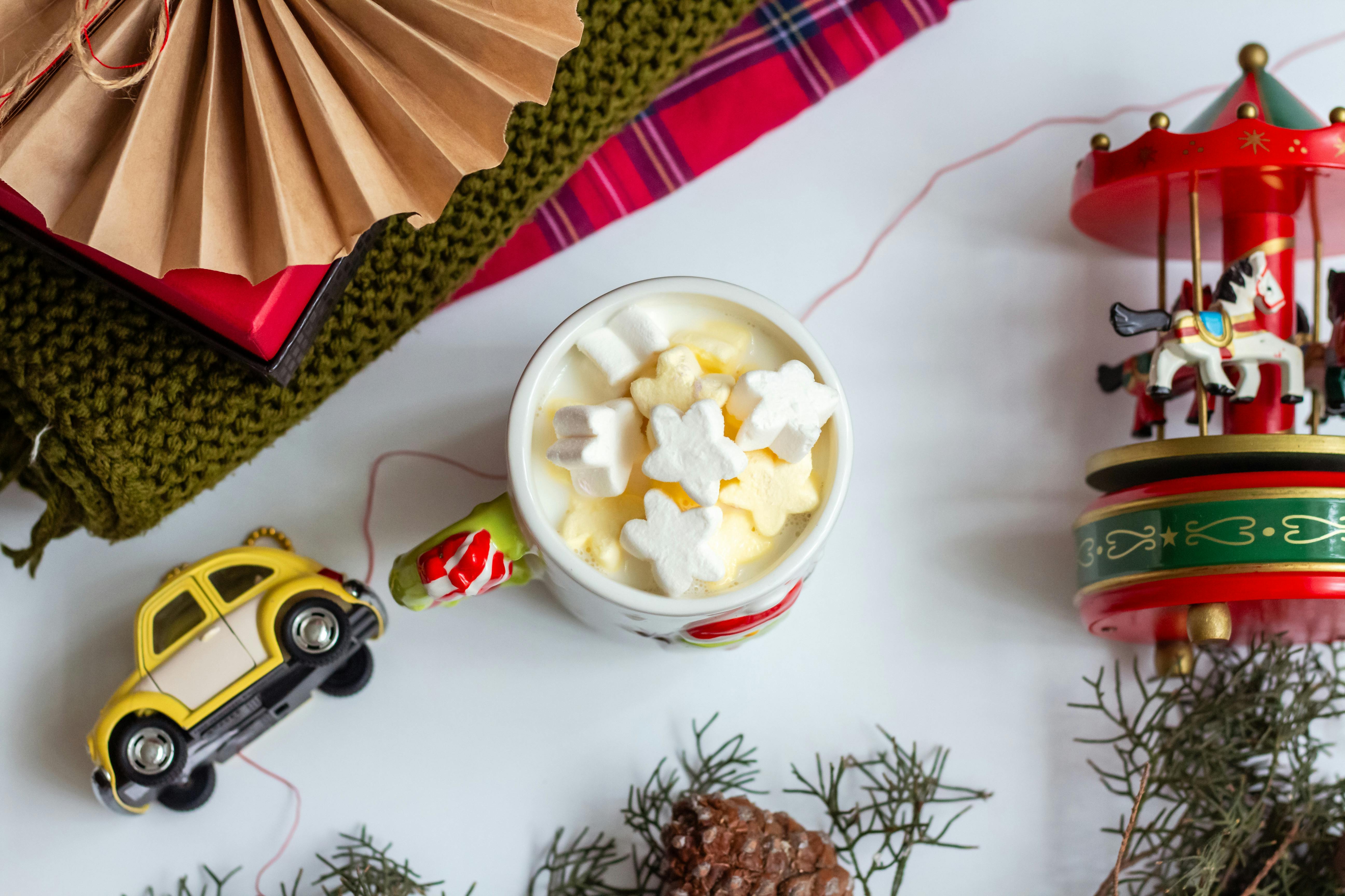 Cozy festive flat lay with hot cocoa, marshmallows, and holiday toys.