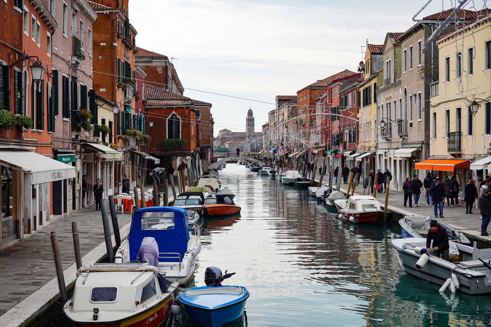 A vibrant daytime view of Murano's canal with boats and colorful houses.