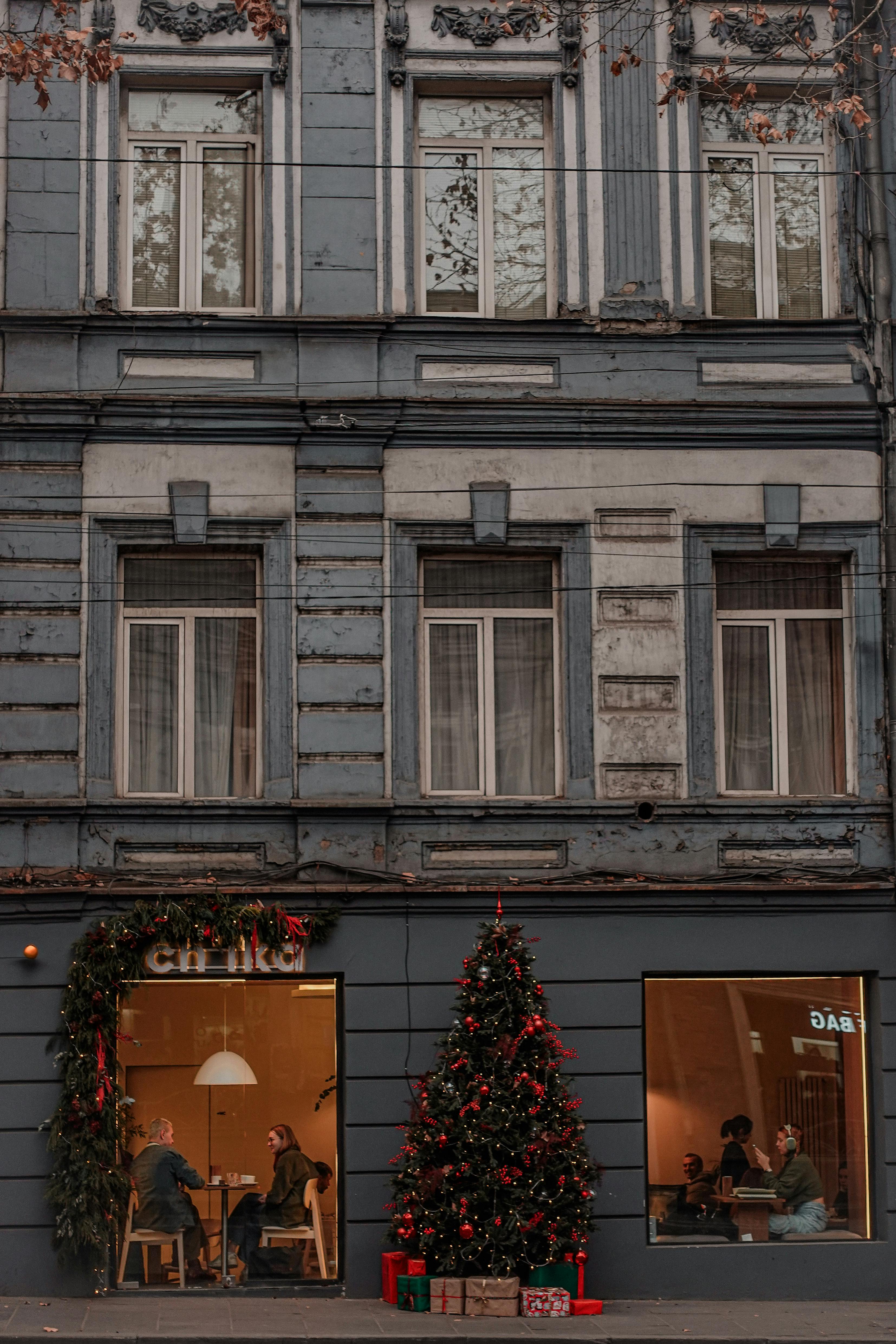 Rustic café exterior with festive Christmas decor and patrons enjoying a cozy atmosphere.