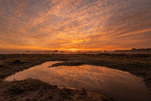 Breathtaking sunset view at Mantinge wetlands in Drenthe, Netherlands reflecting vivid skies.