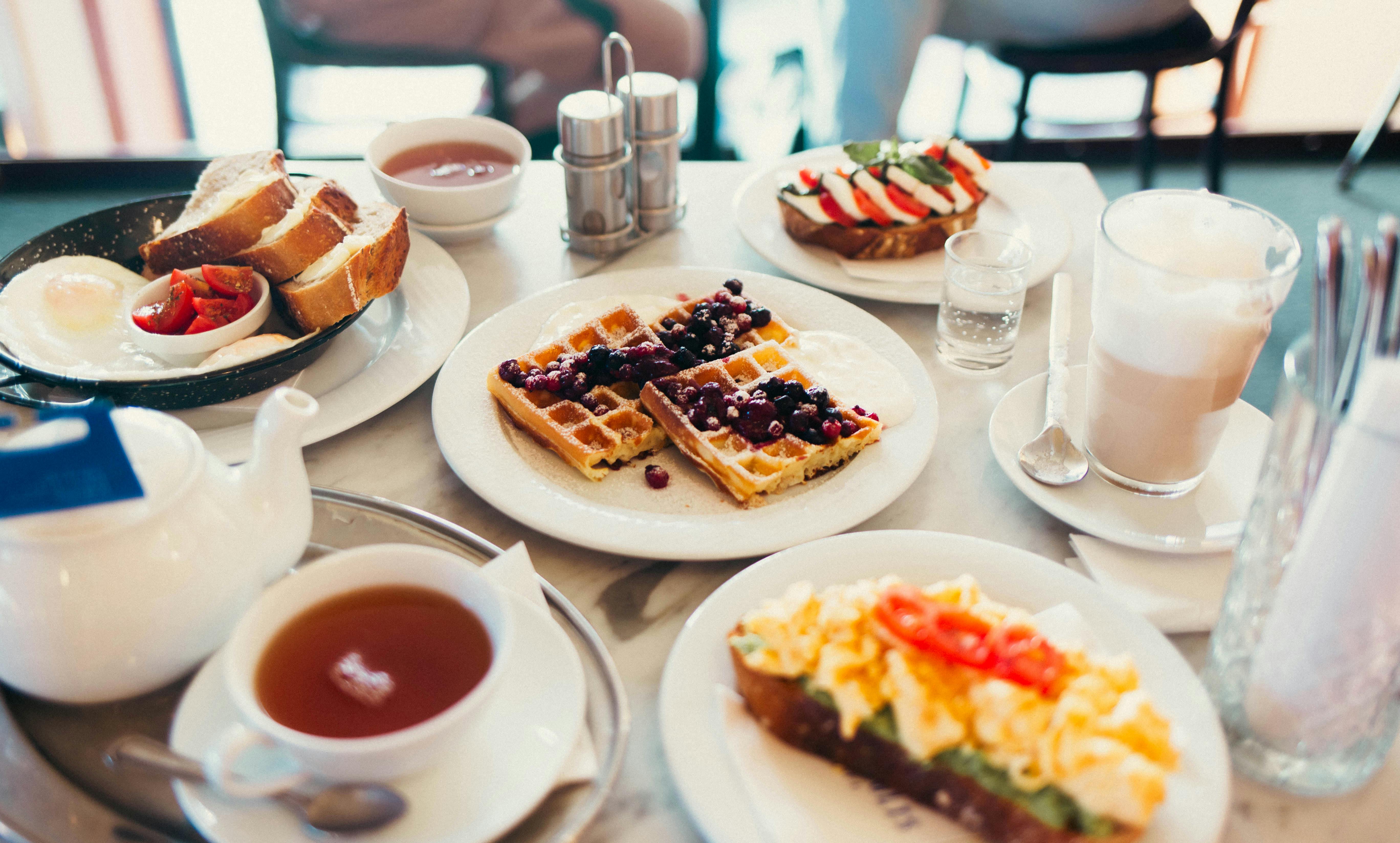A vibrant brunch spread with waffles, avocado toast, and tea in a Brno cafe.