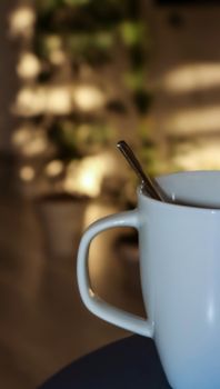 A close-up of a coffee mug with a spoon in warm indoor lighting, perfect for cozy morning scenes.