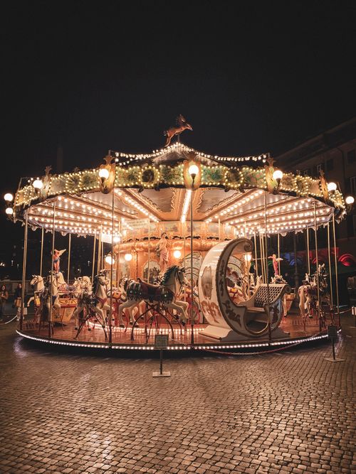 Free Beautifully illuminated carousel at night in Rome's charming piazza. Stock Photo