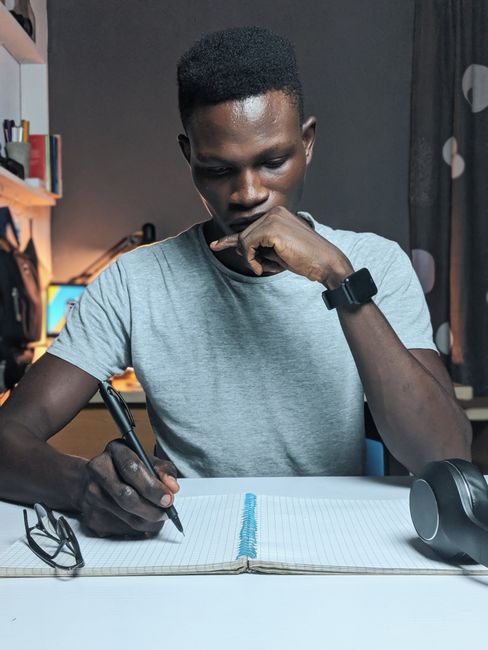 Man deeply focused while writing in a notebook on a desk with a thoughtful expression. Man deeply focused while writing in a notebook on a desk with a thoughtful expression.