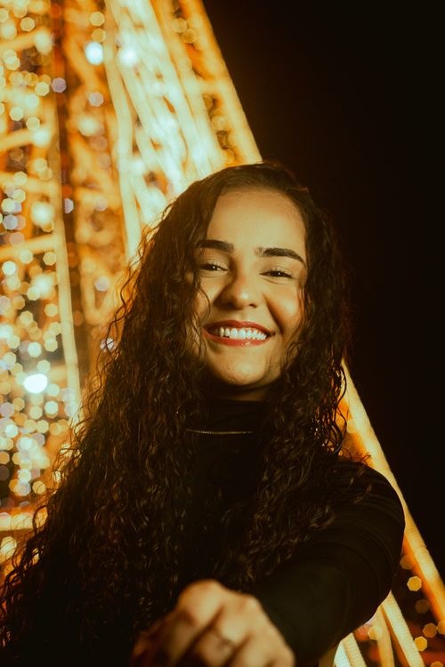 Free Young woman smiling in front of festive lights at night in Recife, Brazil. Stock Photo