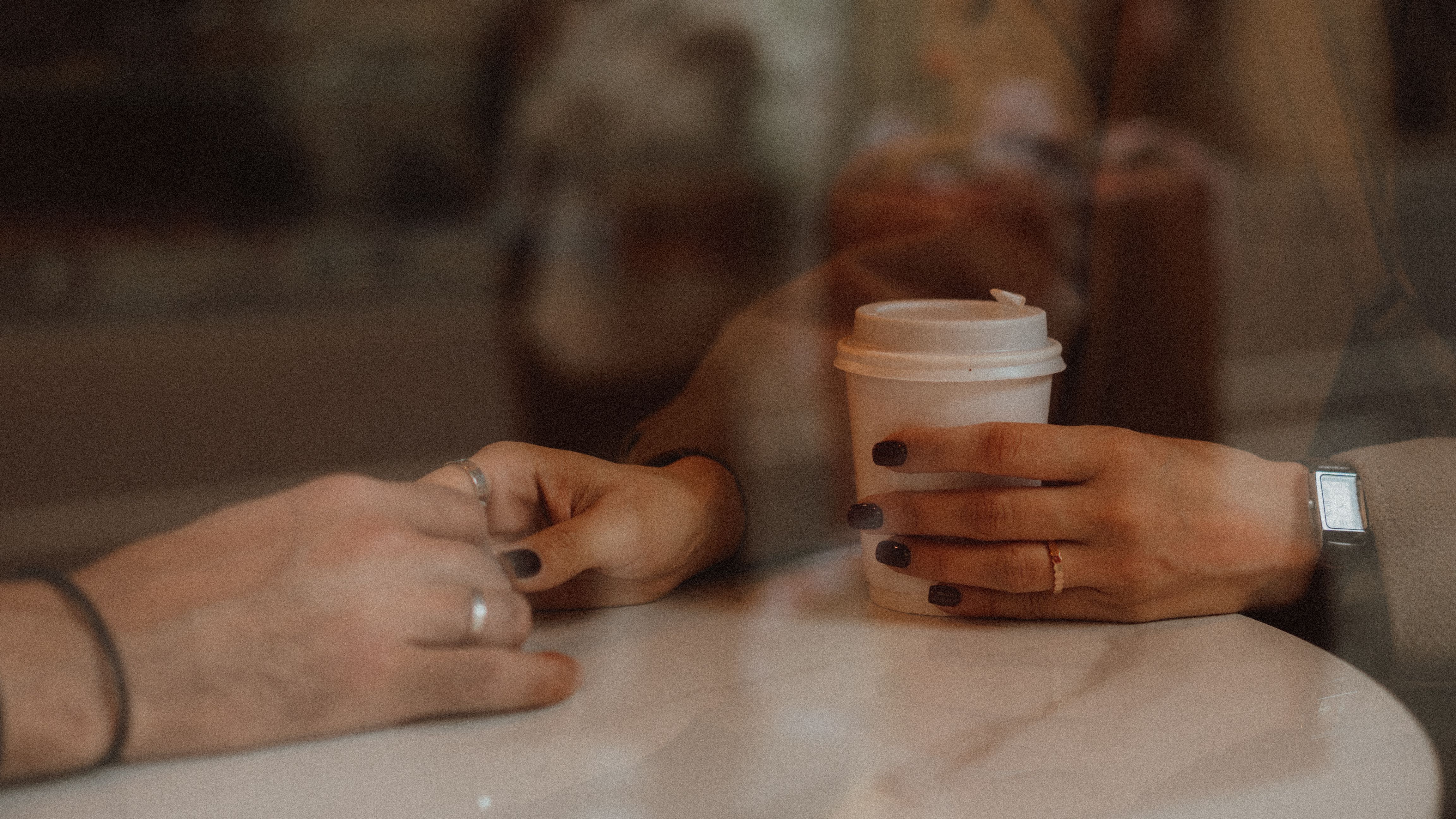 Free Close-up of hands holding coffee cups at a cafe, capturing a warm and intimate moment. Stock Photo