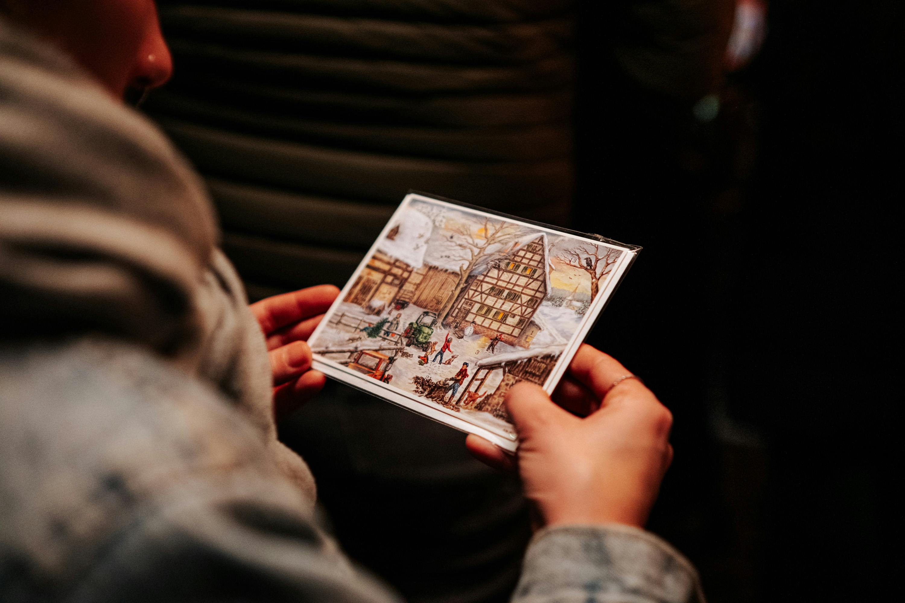 hands holding winter scene postcard indoors