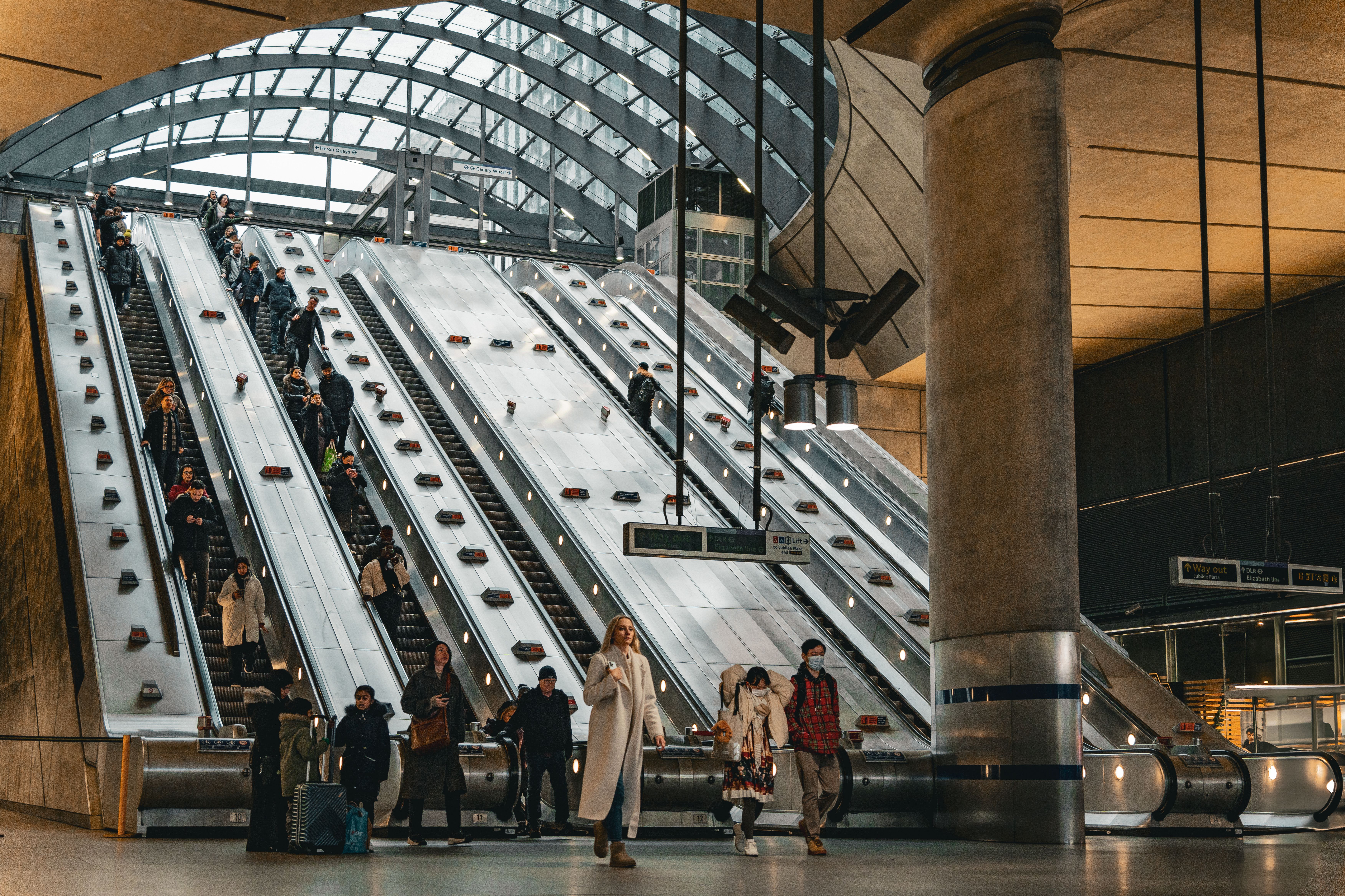 People commuting on escalators inside Canary Wharf Station, London.