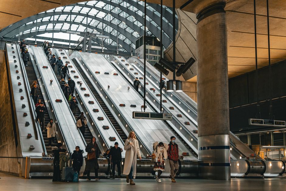 People commuting on escalators inside Canary Wharf Station, London.