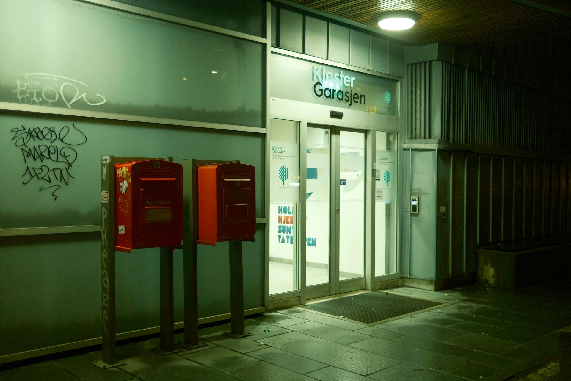 Night view of urban entrance with red mailboxes and modern architecture.