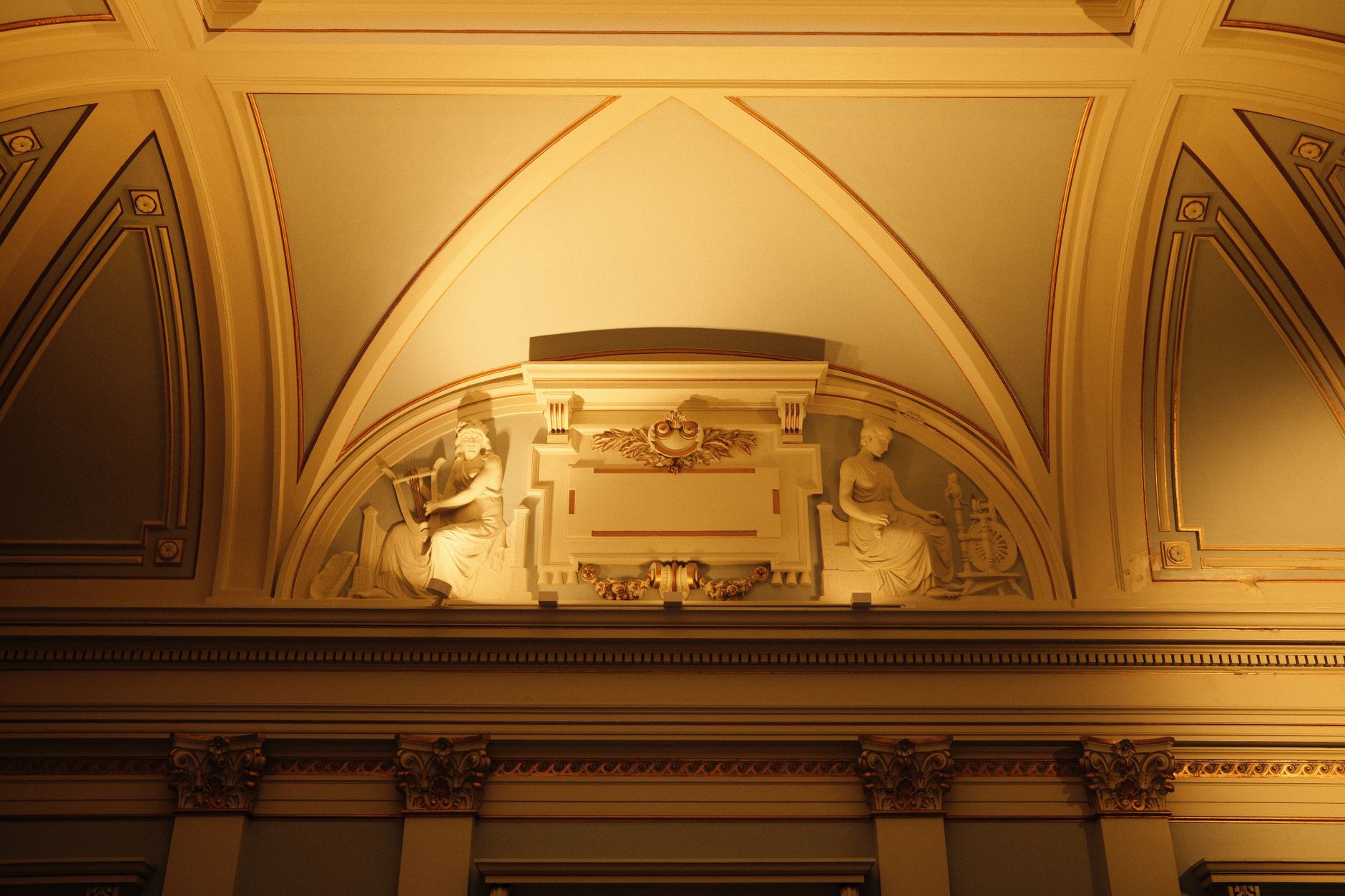 An ornate ceiling with classical sculptures in soft, warm lighting.