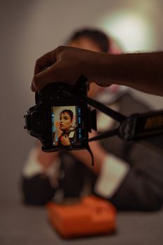 A DSLR camera captures a portrait of a person in a studio setting.