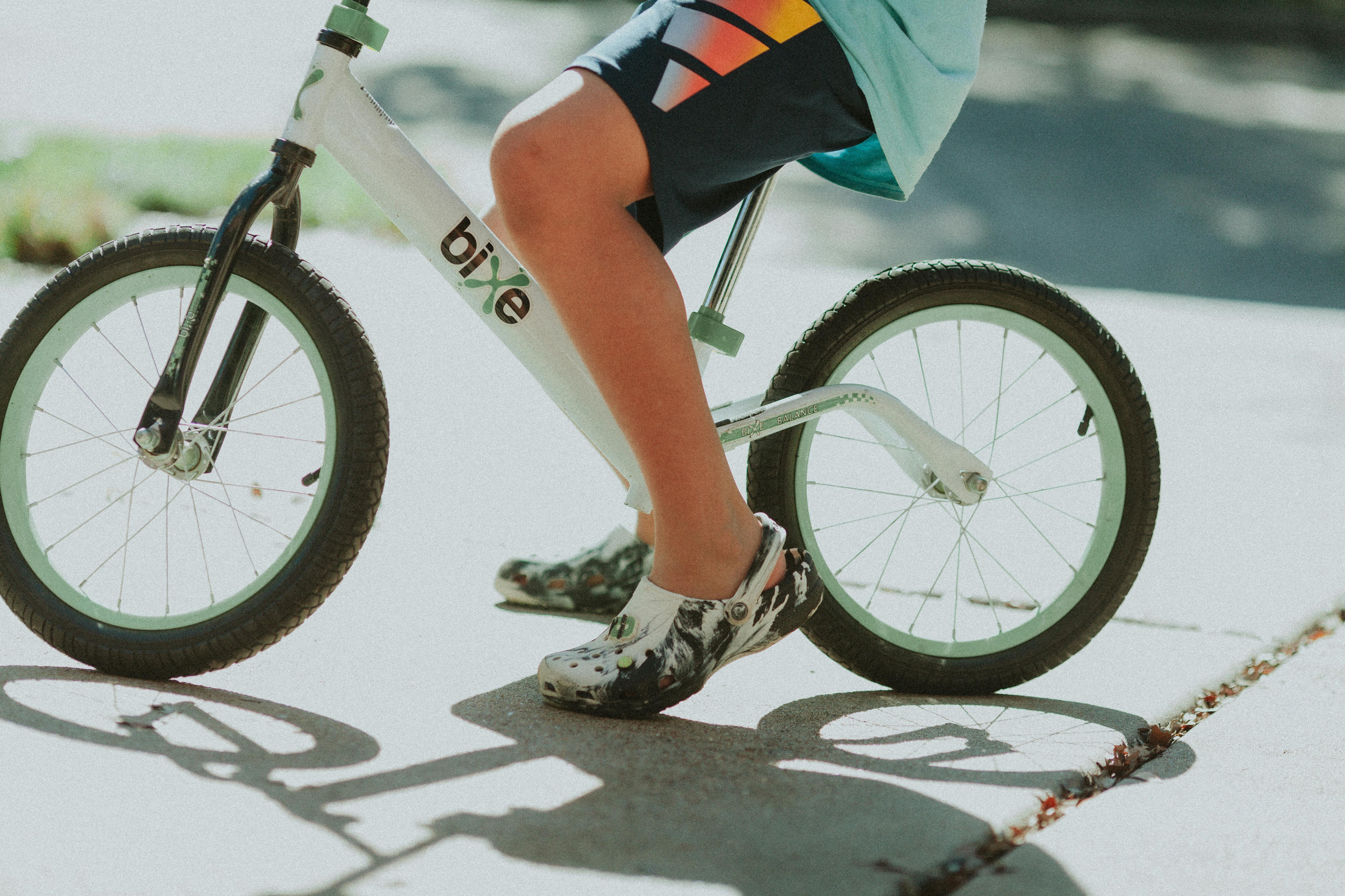 Young child on a white balance bike enjoying a sunny outdoor playtime.